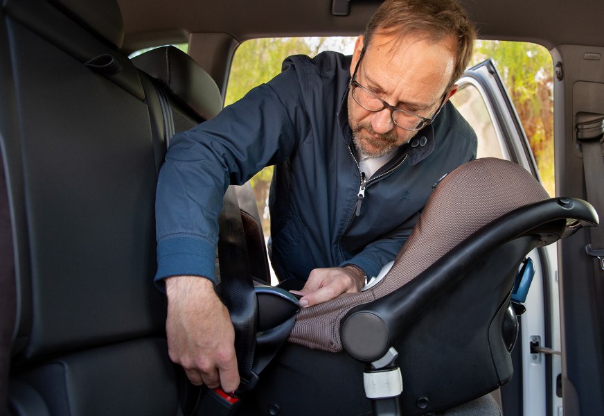 Man adjusting a baby capsule car seat 