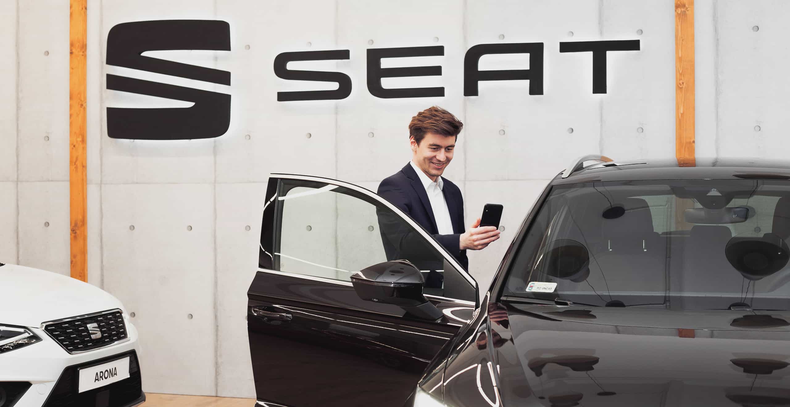 Uśmiechnięty doradzca SEAT-a stojący przy otwartych drzwiach samochodowych