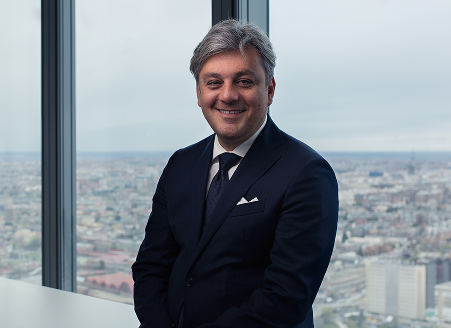 SEAT President Luca de Meo professional headshot with a view of a city in the background