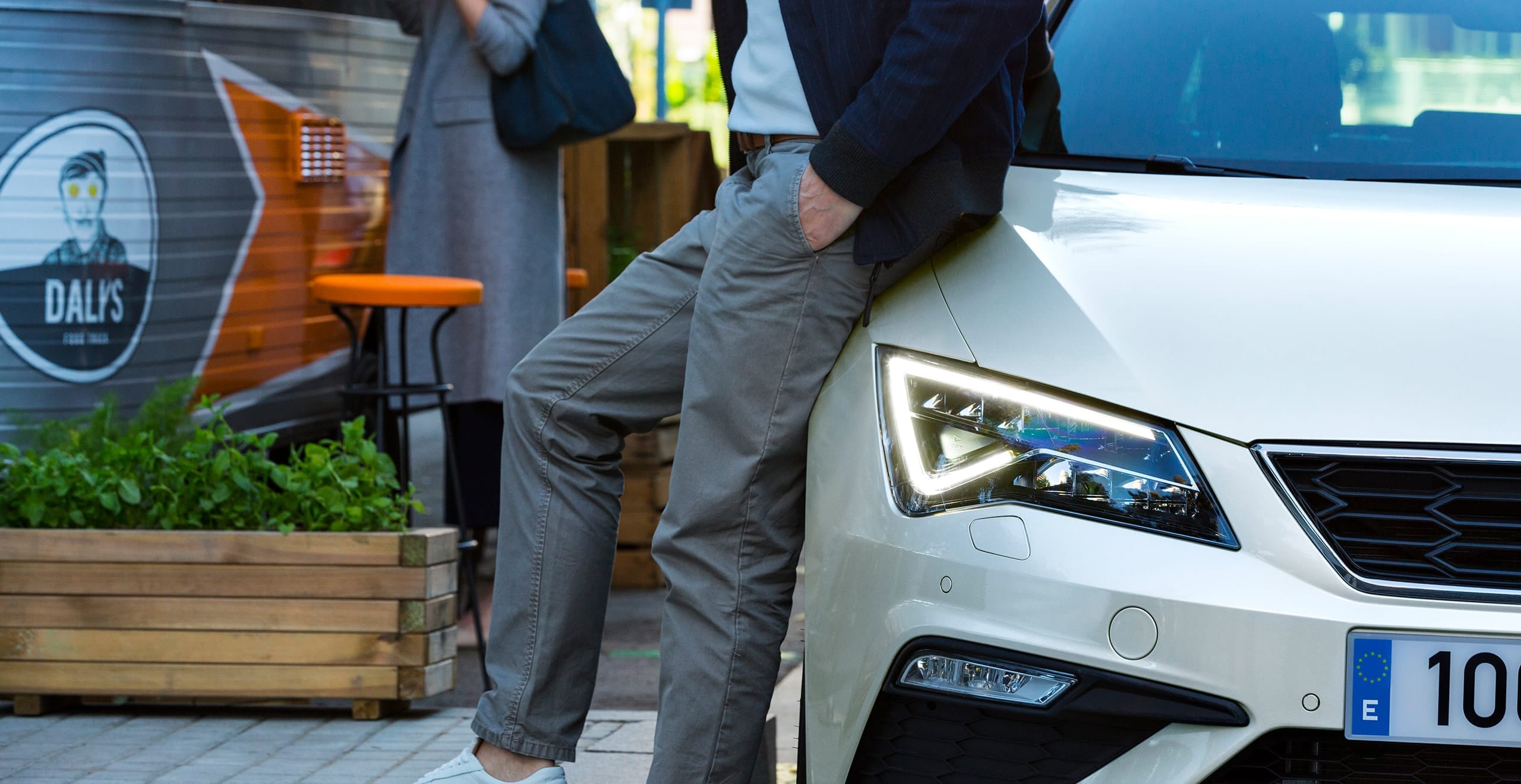 SEAT Service and Maintenance – suited man leaning on the hood of a SEAT hatchback car