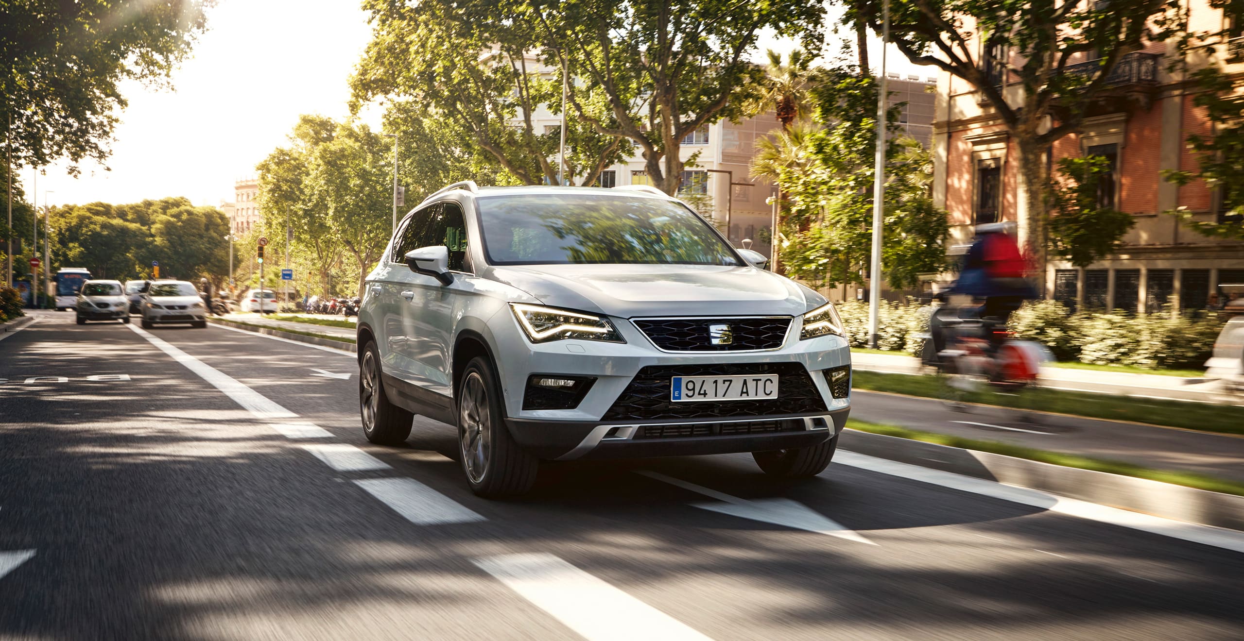 SEAT new car services and maintenance five year warranty – SEAT Ateca SUV driving on a road beside trees