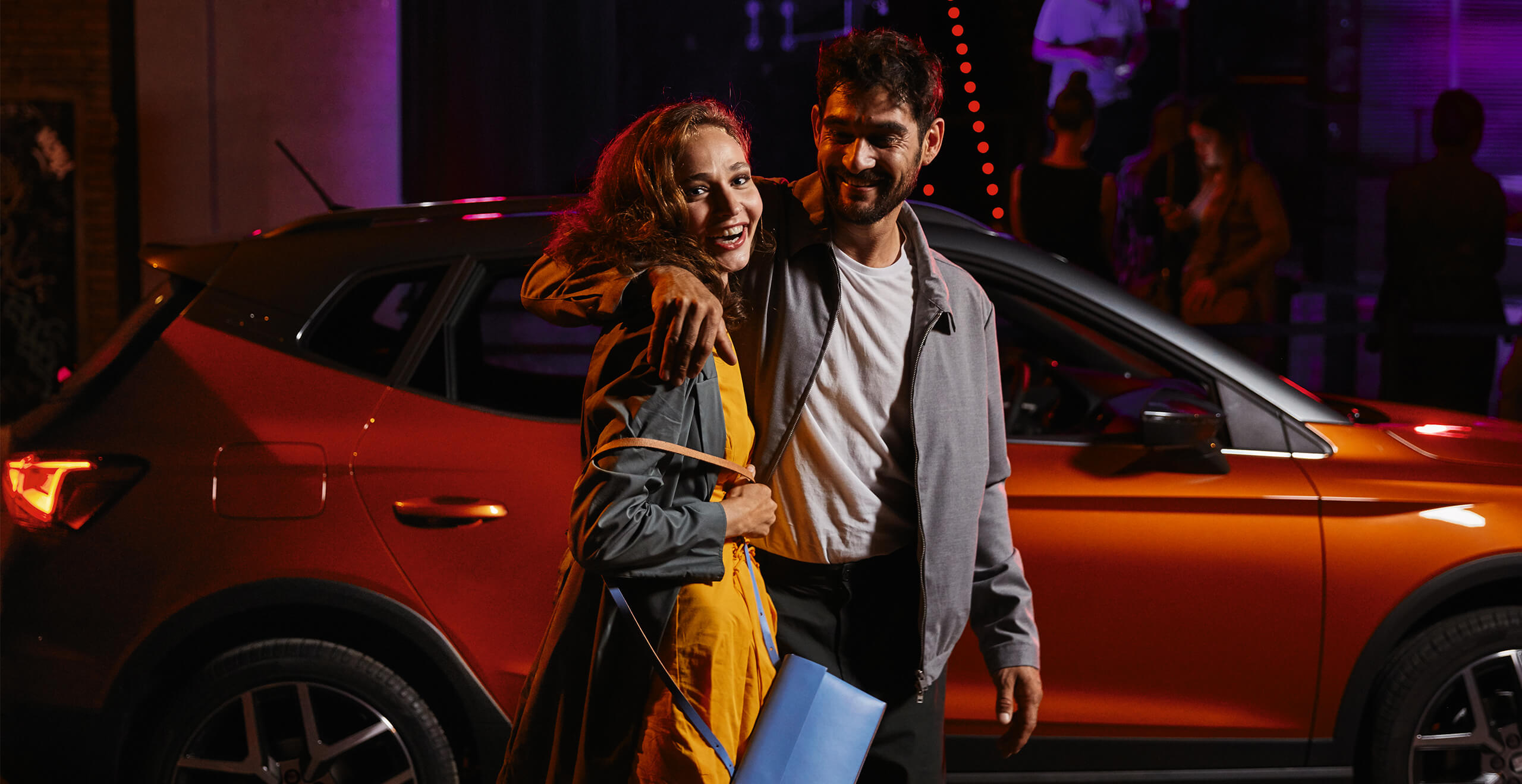 SEAT Service and maintenance – young couple walking at night in front of a SEAT Arona Crossover SUV