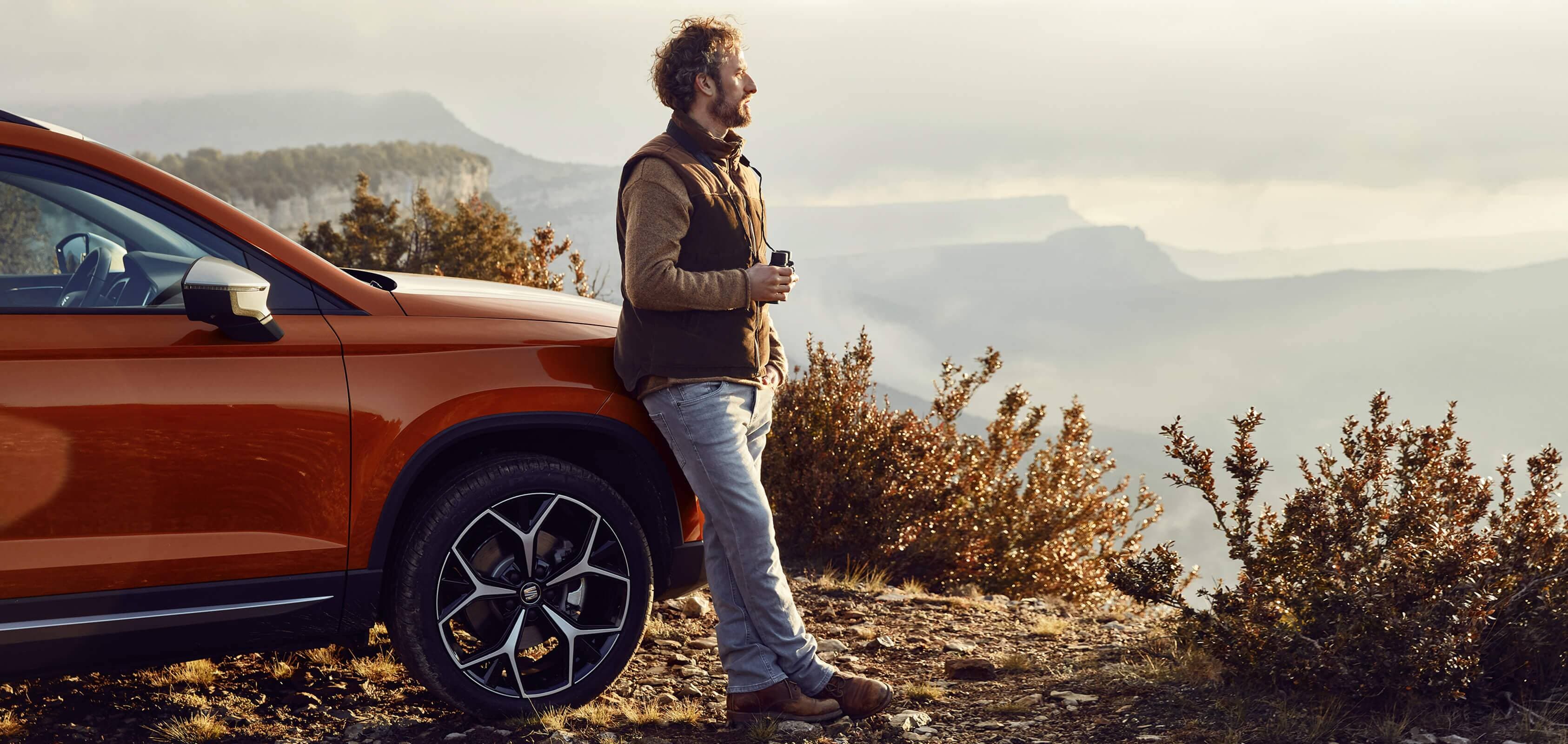 Front view cropped image of a man leaning on the bonnet of a SEAT new car